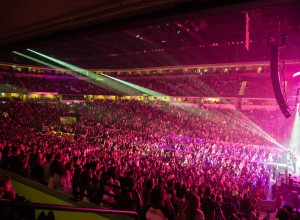 Arena full of people with pink lights shining on stage